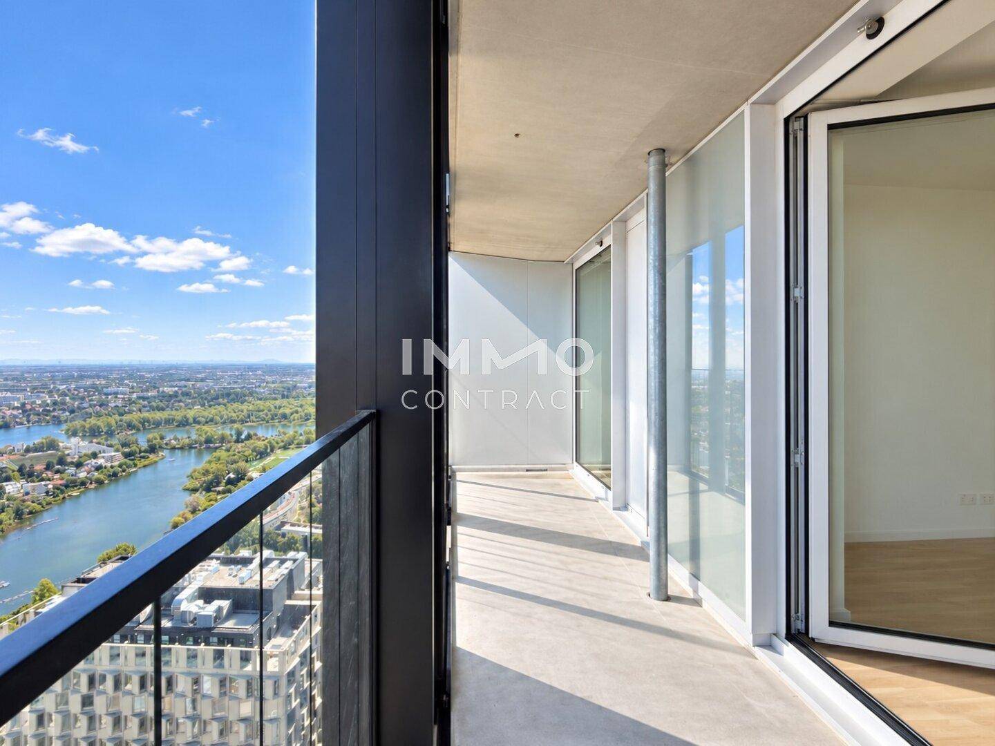 Langer Balkon mit Glasgeländer und weitem Blick auf die Stadt und den Fluss.