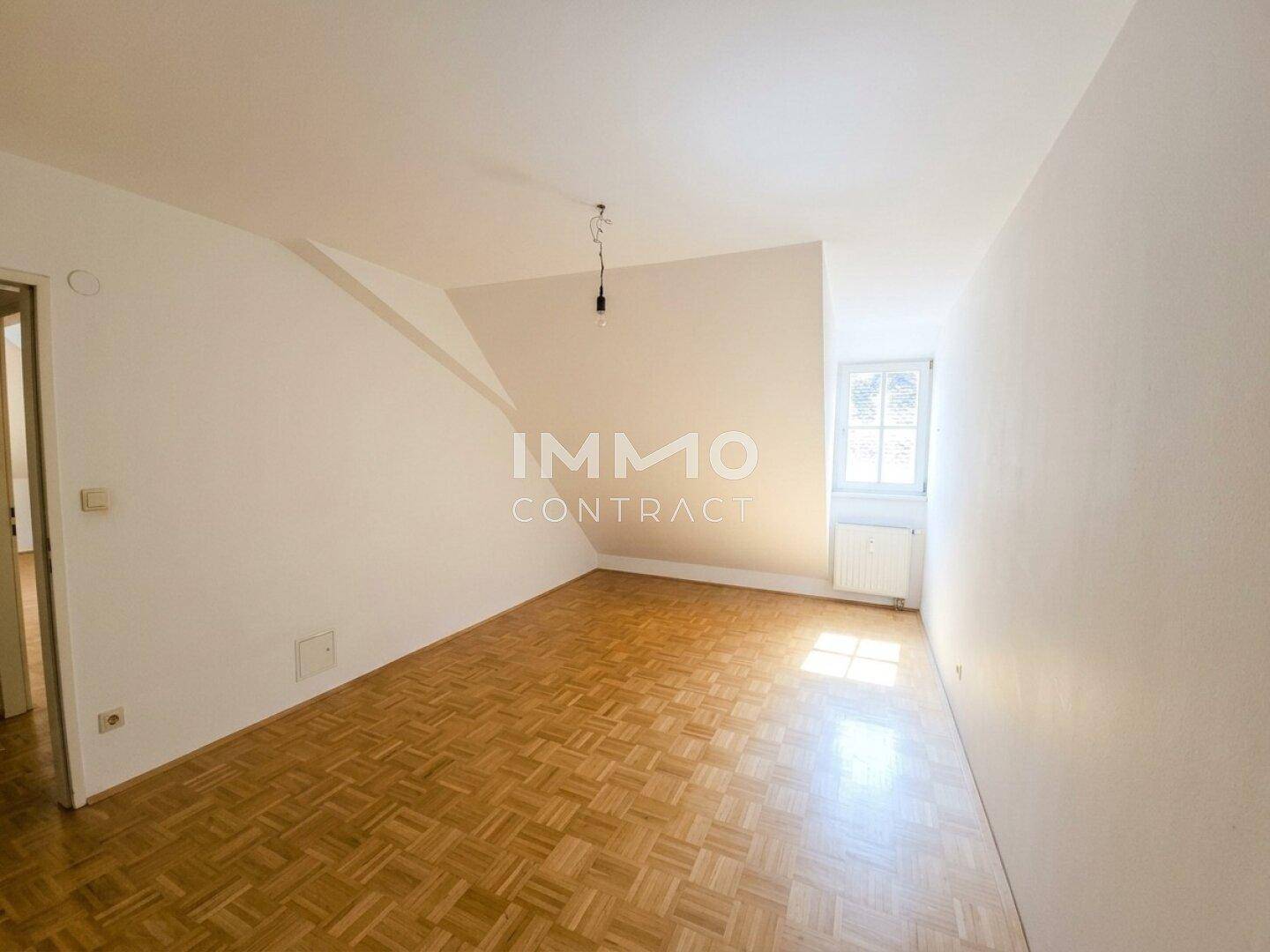 Heller Raum im Dachgeschoss mit Parkettboden und einem Fenster, bereit zur individuellen Gestaltung.