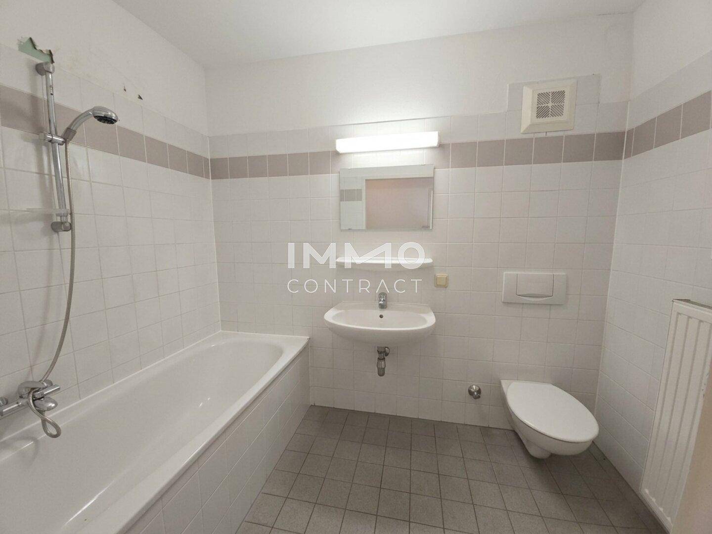 Funktionales Badezimmer mit Badewanne, Waschbecken, Toilette und weißen Fliesen.