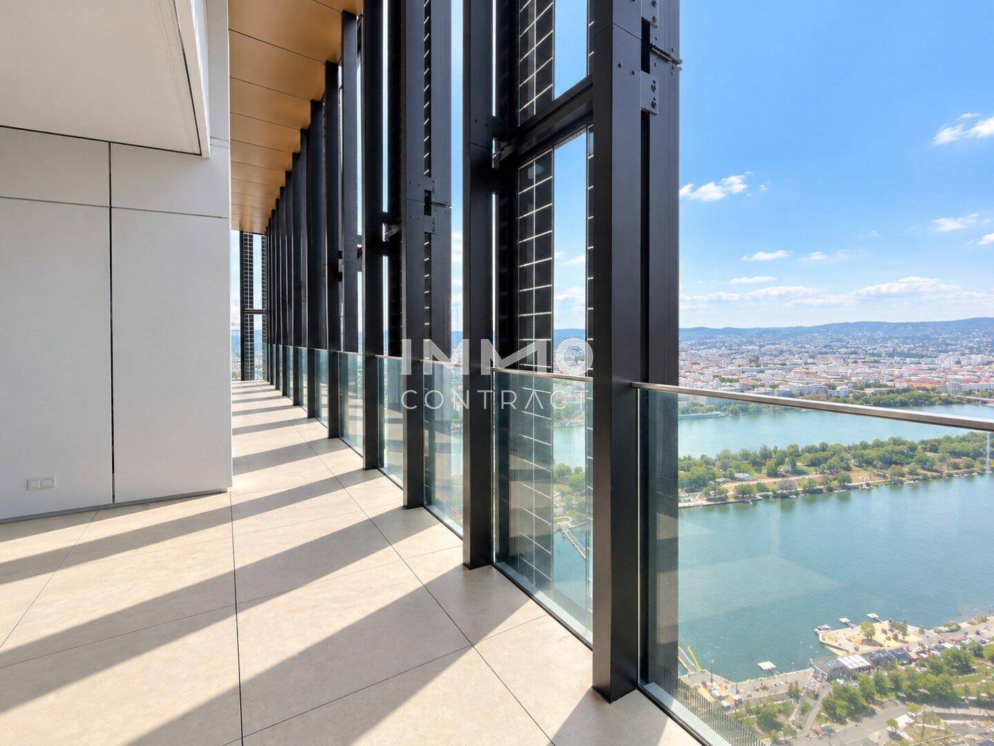 Geräumiger Balkon mit Fliesenboden und weitem Blick über die Stadt und das Wasser.