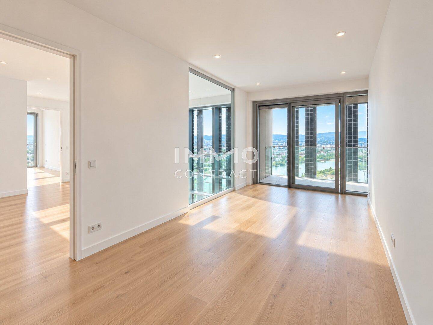 Helles Schlafzimmer mit Holzboden und großen Fenstern, die einen weiten Blick auf die Stadt bieten.