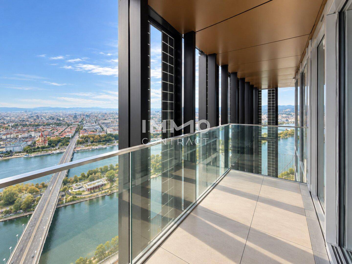 Moderner Balkon mit Glasgeländer und beeindruckendem Ausblick auf die Stadt und die Donau.
