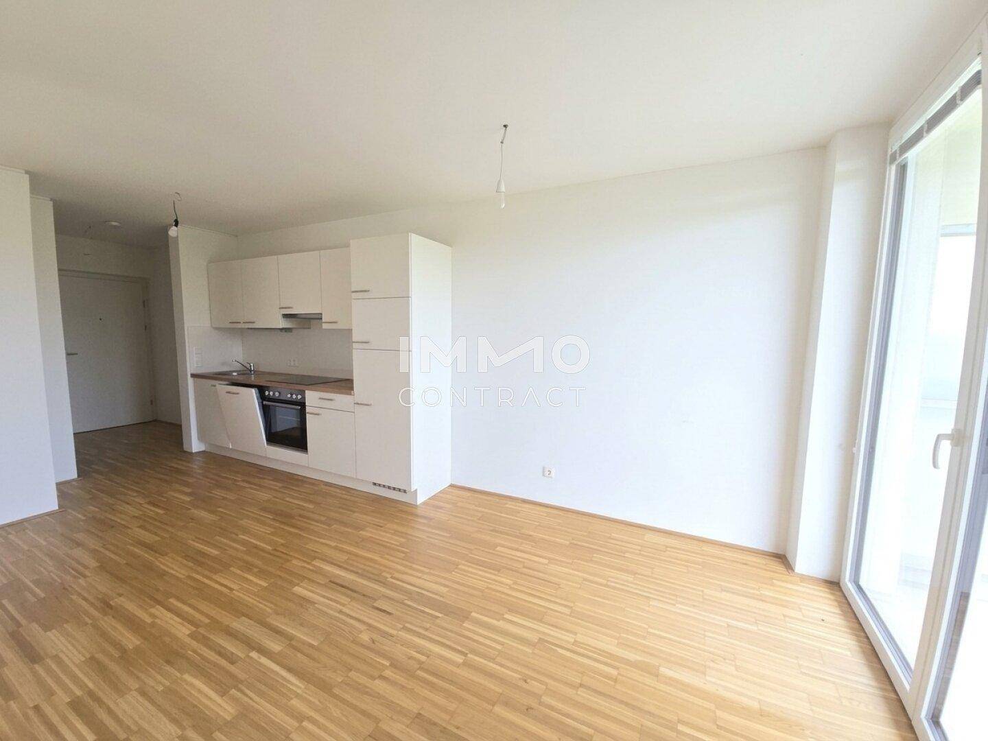 Geräumiger offener Wohnbereich mit moderner Küchenzeile und hellem Parkettboden, ideal für geselliges Beisammensein.