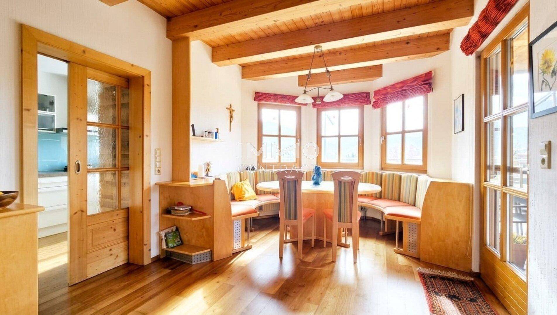 Rustikaler Essbereich mit Holzbalkendecke, Eckbank und Zugang zur Küche durch eine Schiebetür.