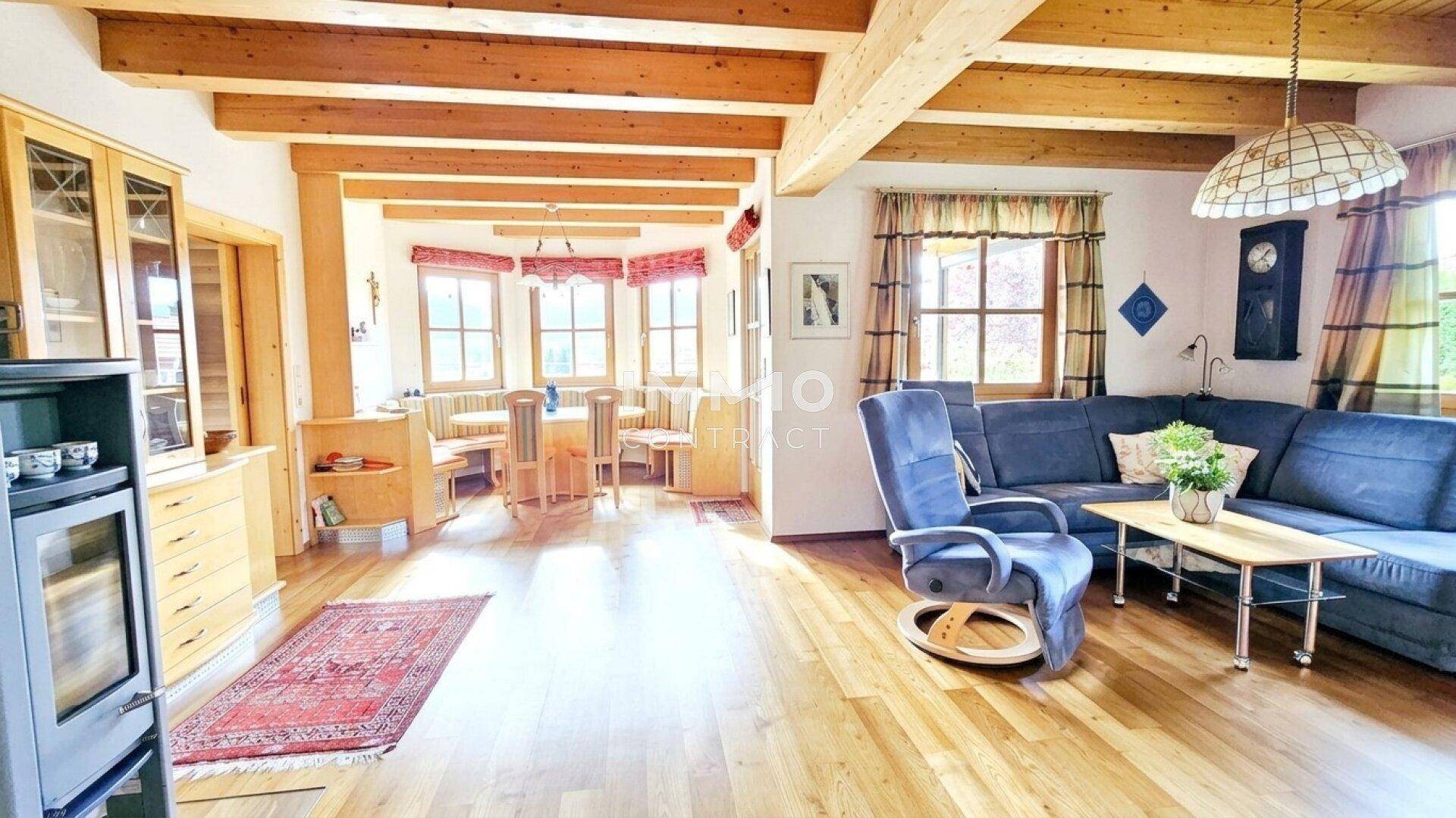 Offener Wohn- und Essbereich mit Holzbalkendecke, Kaminofen und Holzboden in traditionellem Stil.