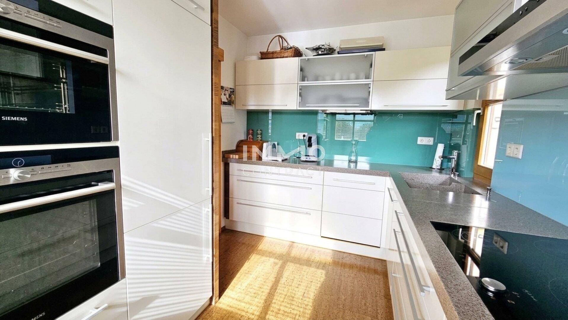 Helle Einbauküche mit modernen Siemens-Geräten, viel Stauraum und Fenster für Tageslicht.