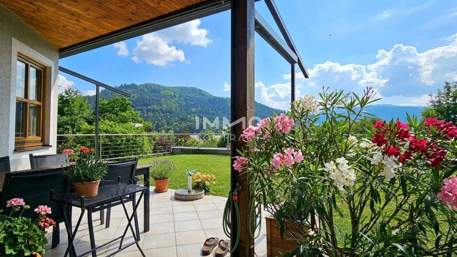 Gemütliche Terrasse mit Gartenmöbeln, blühenden Pflanzen und weitem Bergblick.
