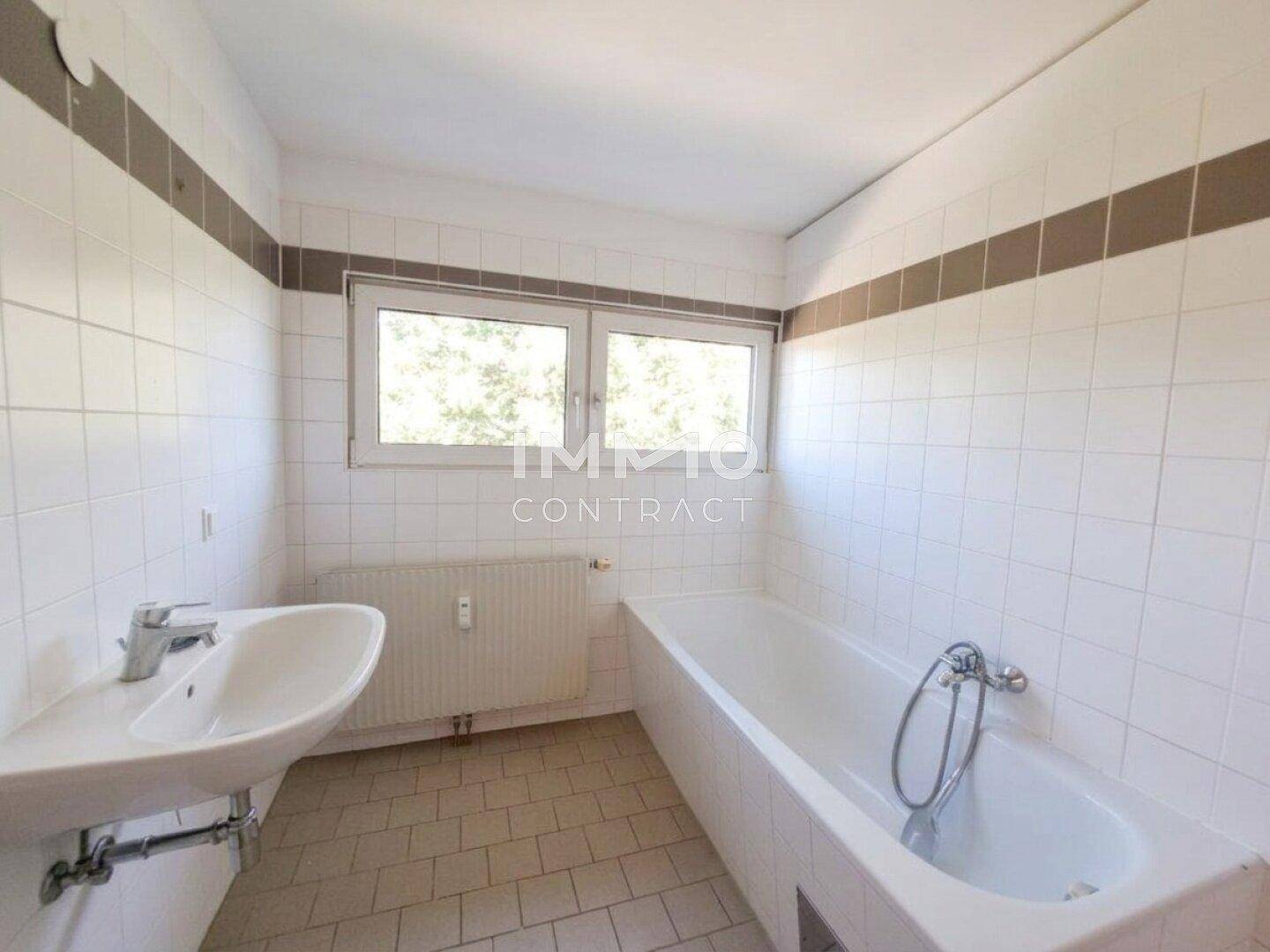 Badezimmer mit Badewanne, Waschbecken und Fenster für natürliche Belüftung.