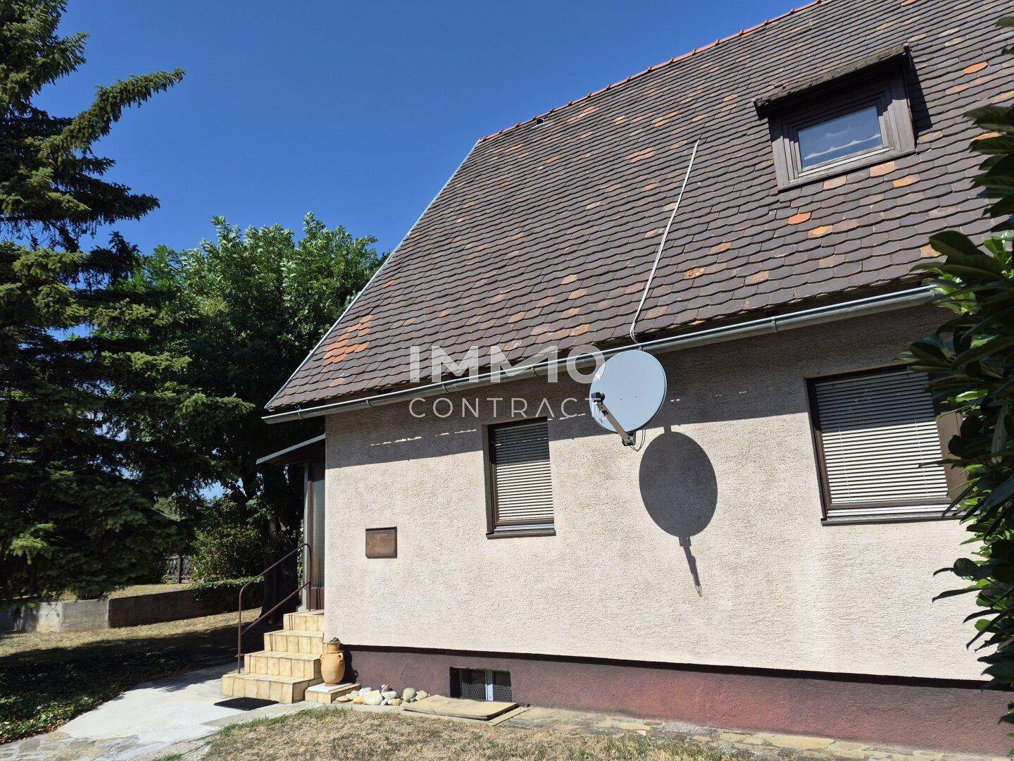 Seitenansicht des Hauses mit Satteldach, Dachfenster und Satellitenschüssel.