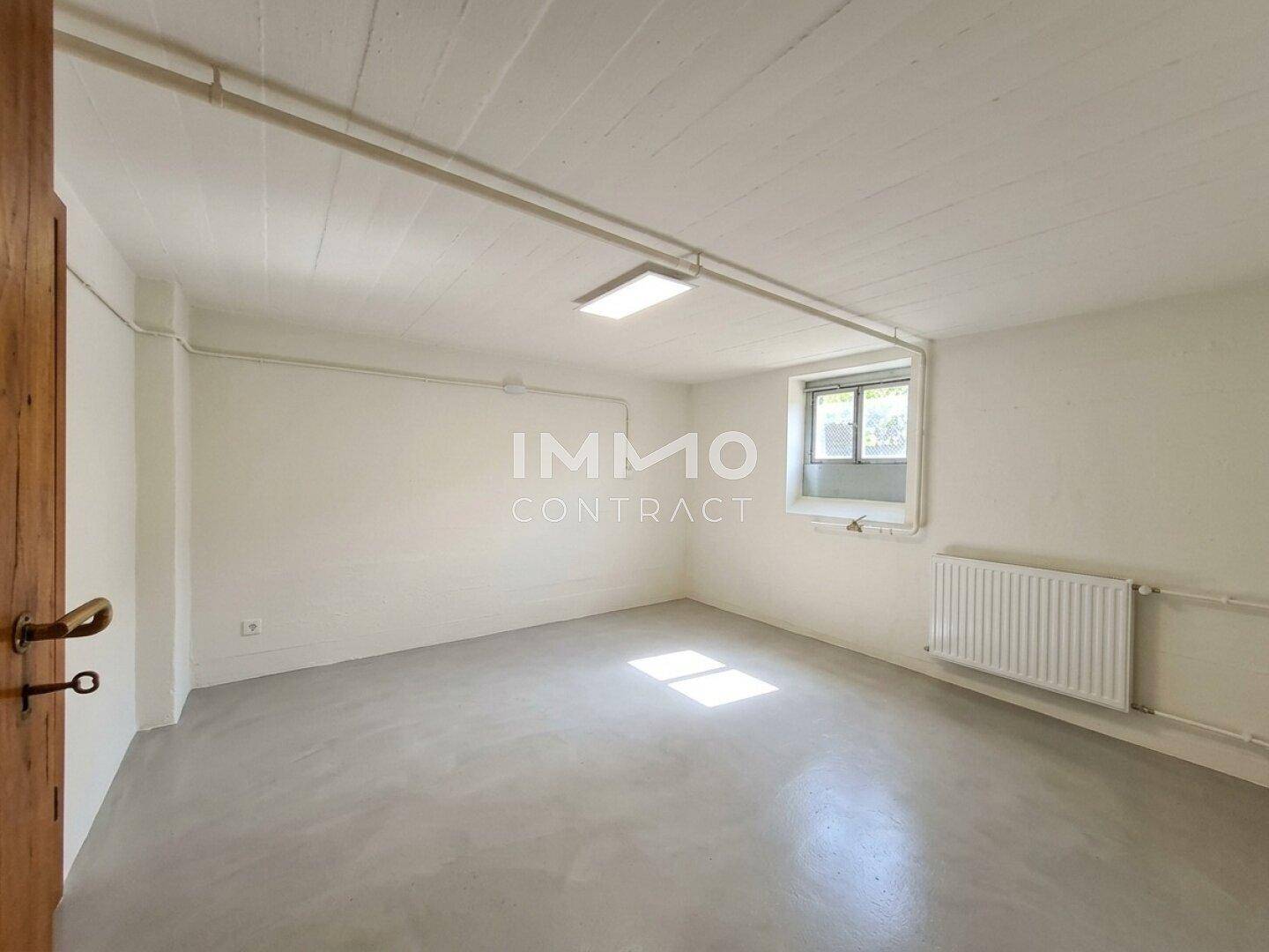 Heller, ausgebauter Kellerraum mit Fenster, Heizkörper und hellem Boden.