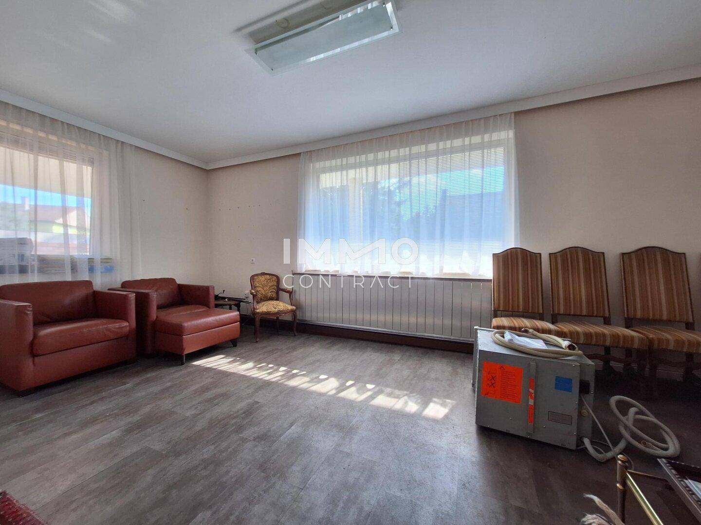 Geräumiger Innenraum mit Laminatboden, großen Fenstern und verschiedenen Sitzgelegenheiten.