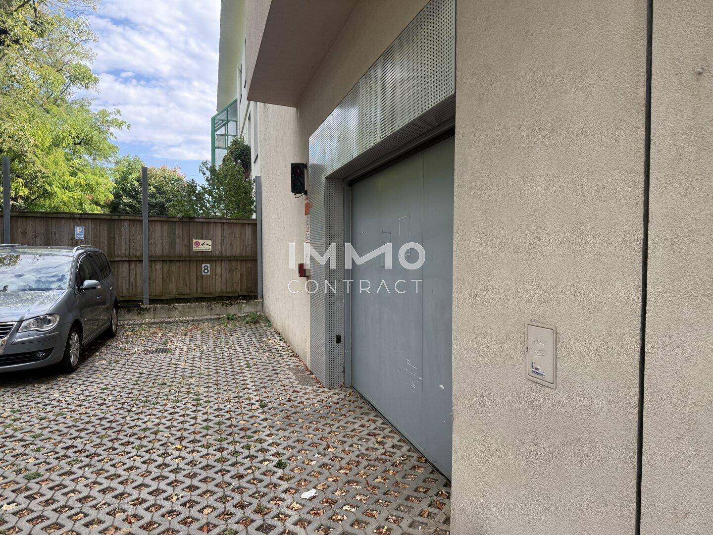 Außenansicht der Einfahrt zu einer Tiefgarage mit zusätzlichem Stellplatz im Freien.