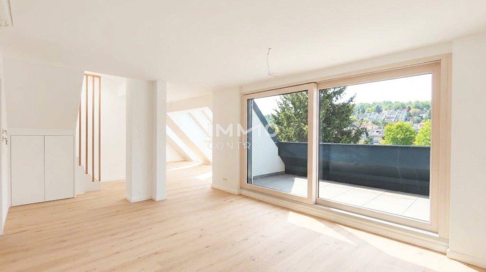 Heller Raum mit Holzboden und großer Schiebetür, die zu einer Terrasse führt.