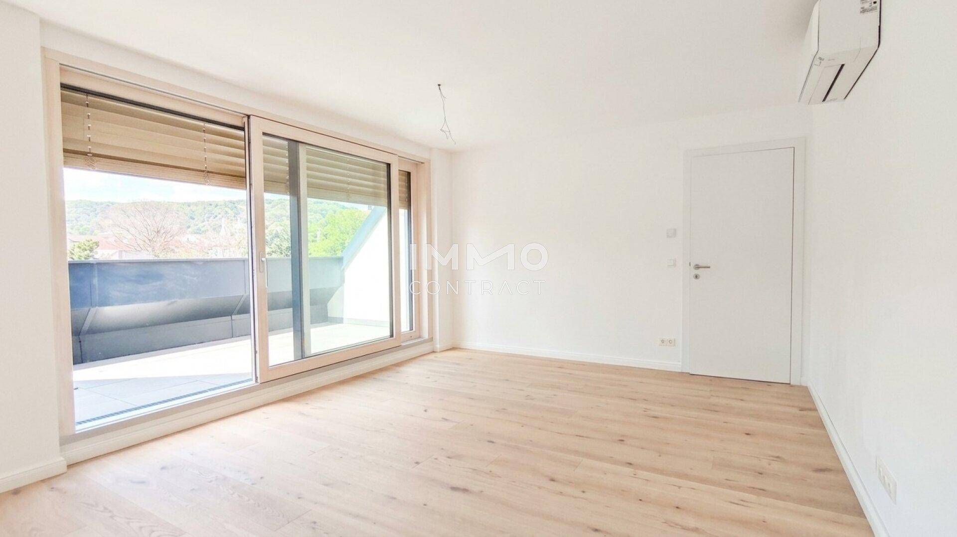 Geräumiger, heller Raum mit Holzboden, Klimaanlage und Zugang zu einer Terrasse.