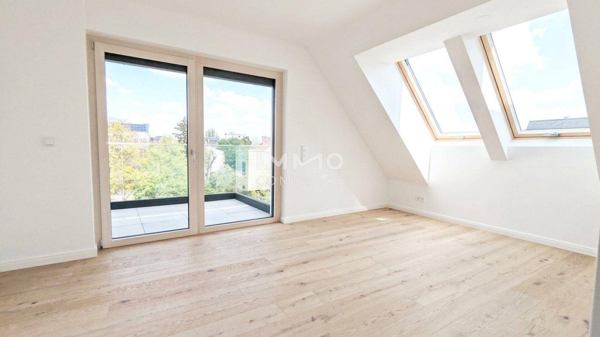 Heller Raum mit Holzboden, Dachfenstern und Zugang zu einer Terrasse.
