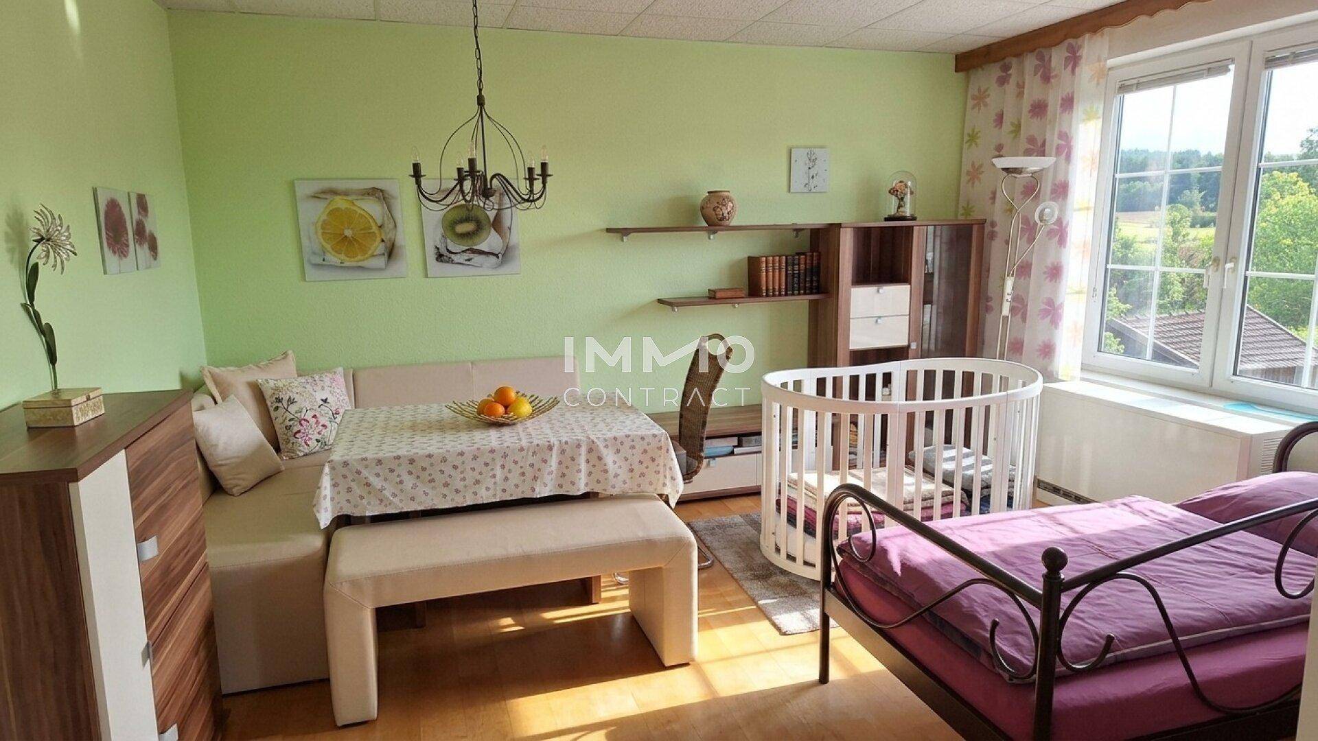 Helles Zimmer mit grün gestrichenen Wänden, einem Babybett und einem Einzelbett.