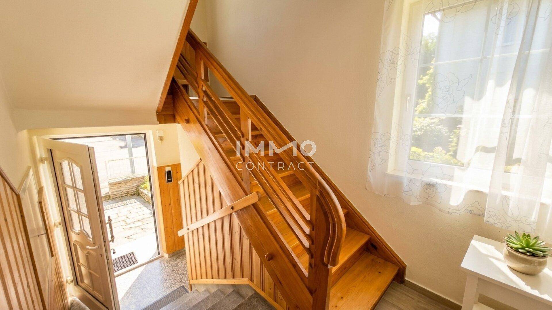 Heller Eingangsbereich mit einer Holztreppe, die in die oberen Stockwerke führt.