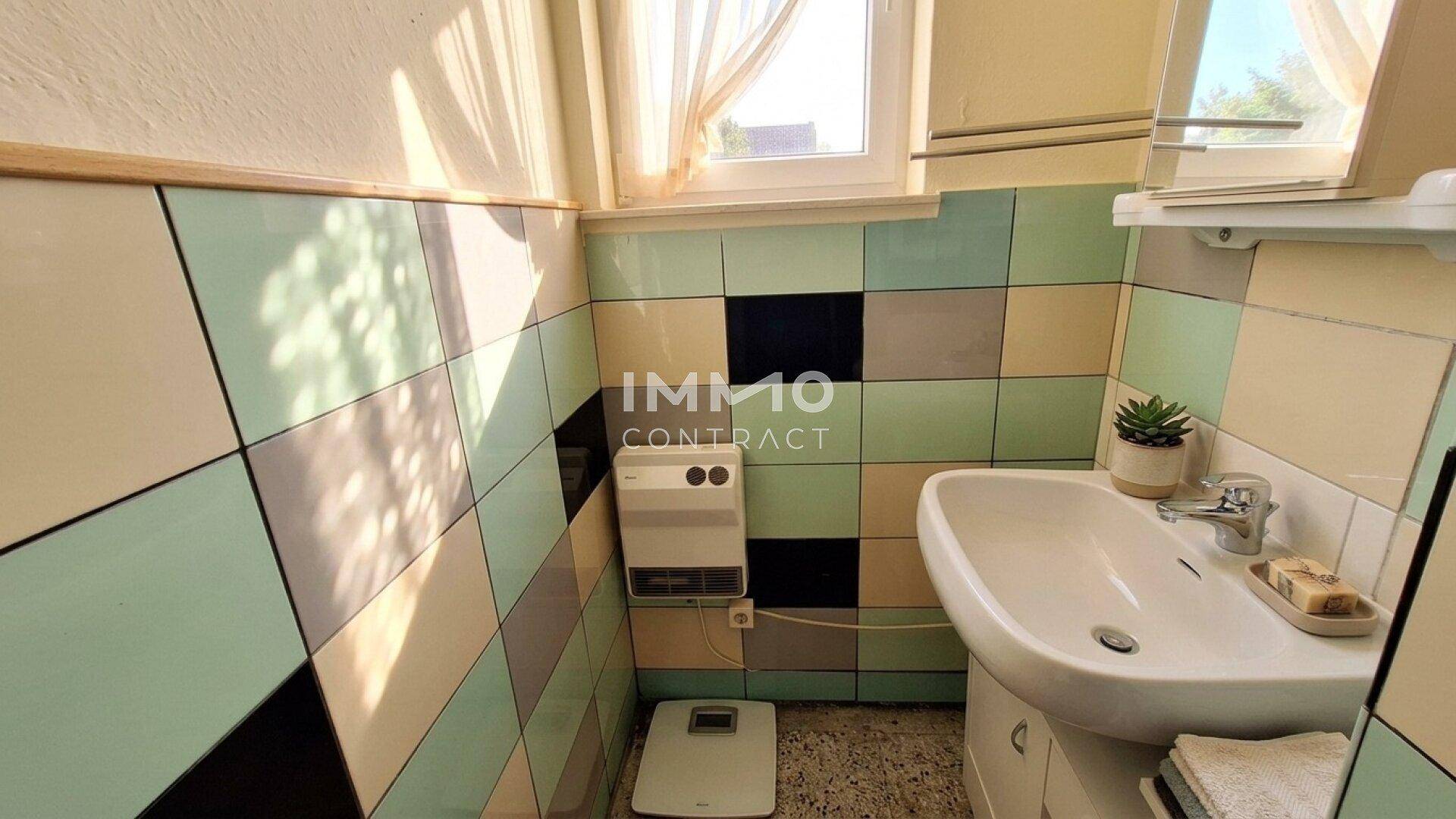 Badezimmer mit farbigen Fliesen in Pastelltönen und einem Waschbecken mit Spiegelschrank.