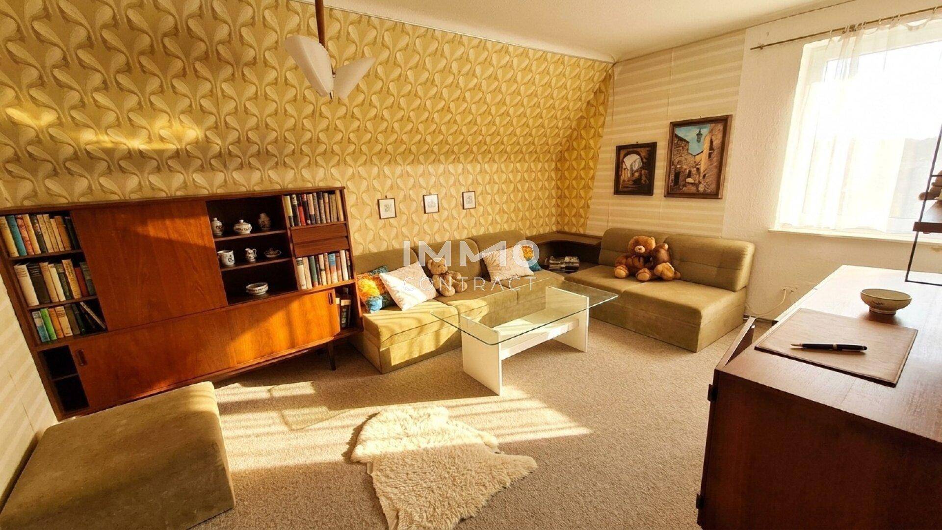 Gemütliches Wohnzimmer mit gemusterter Tapete, bequemen Sofas und einem Couchtisch.