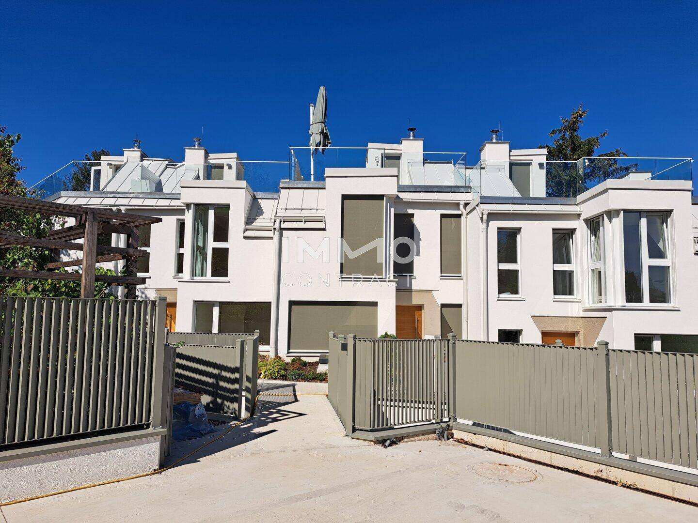 Moderne Reihenhäuser mit weißer Fassade, großen Fenstern und Dachterrassen.