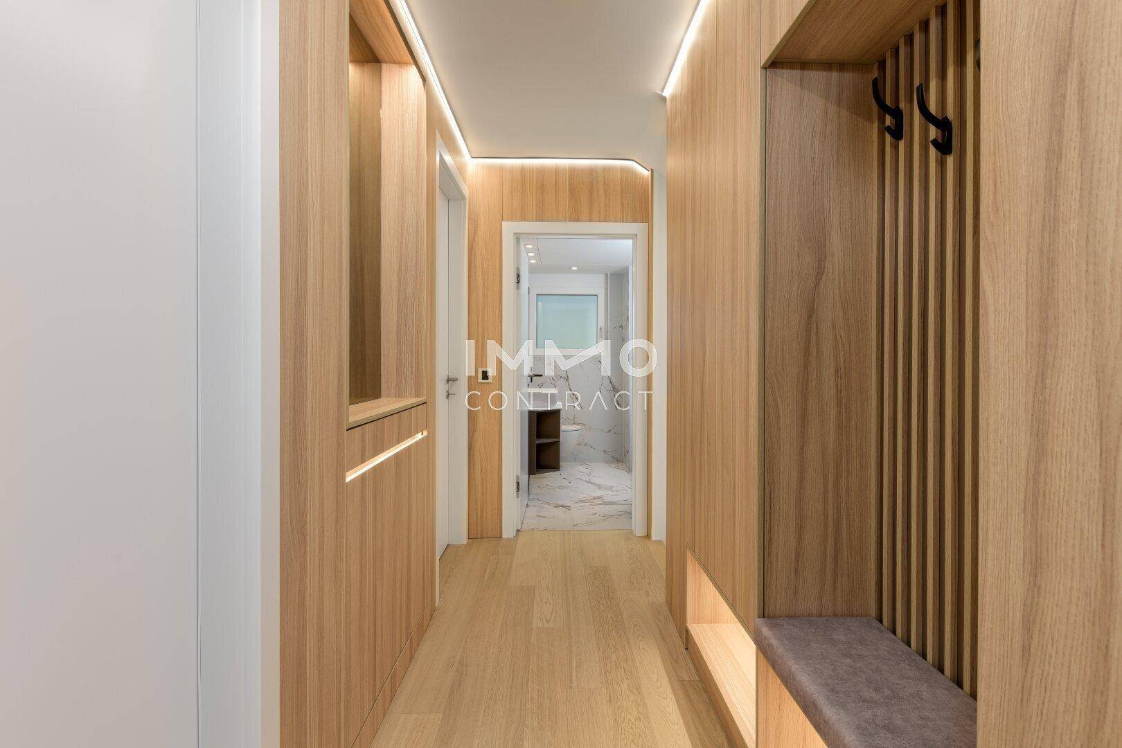Moderner Flur mit Holzelementen, integrierter Garderobe und indirekter Beleuchtung.