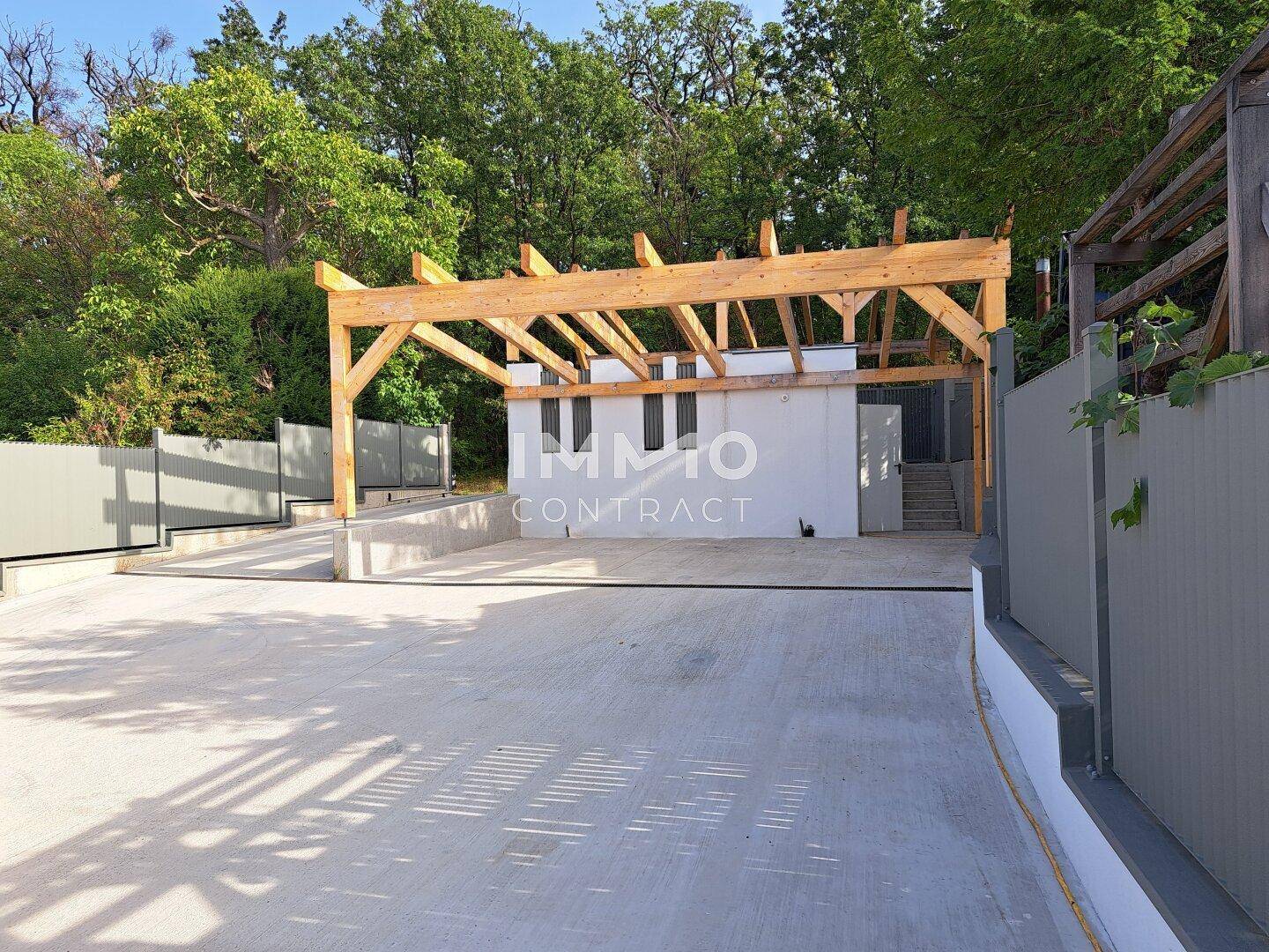 Großer Außenbereich mit Parkplätzen und einer Holzkonstruktion für einen Carport.