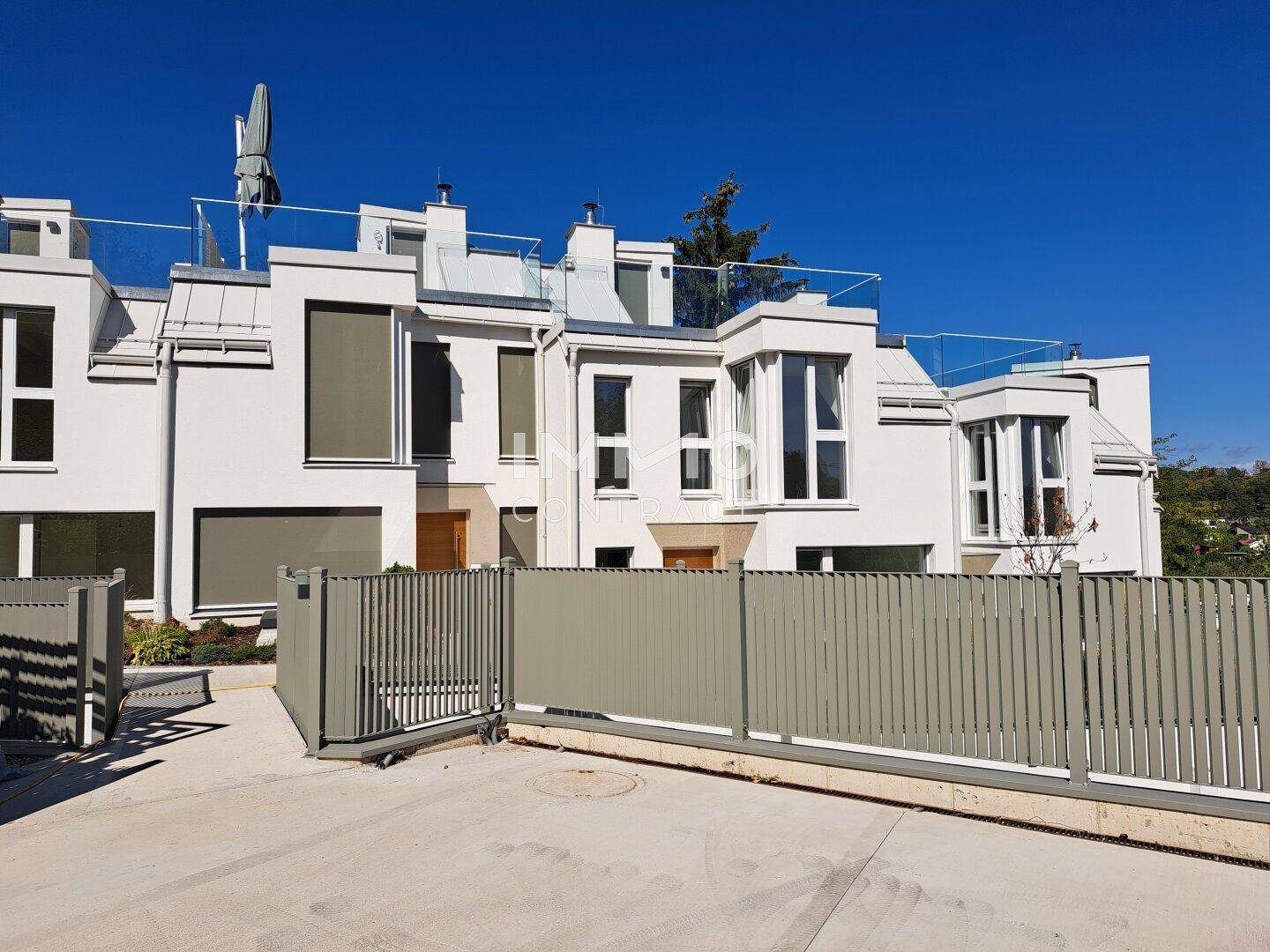 Moderne Reihenhäuser mit weißer Fassade, großen Fenstern und Dachterrassen.
