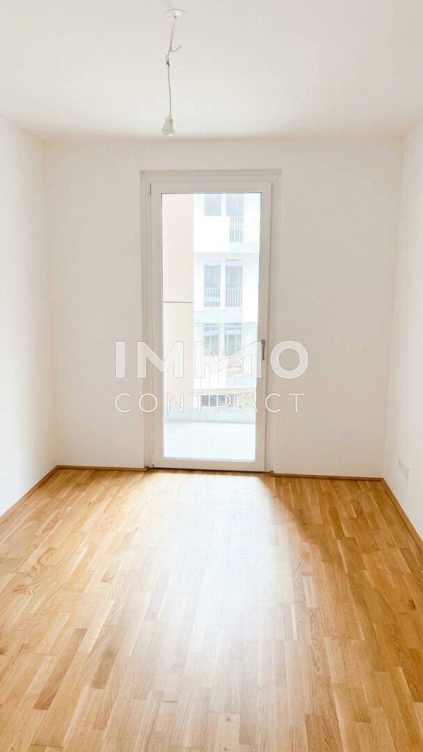 Heller, leerer Raum mit Holzboden und Zugang zu einem Balkon, ideal für individuelle Gestaltung.