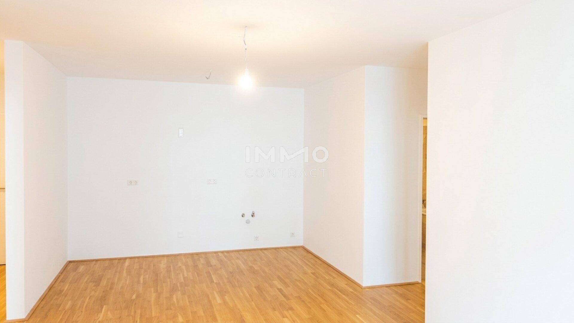 Leerer Raum mit Parkettboden und weißen Wänden, vorbereitet für die Installation einer Küche.