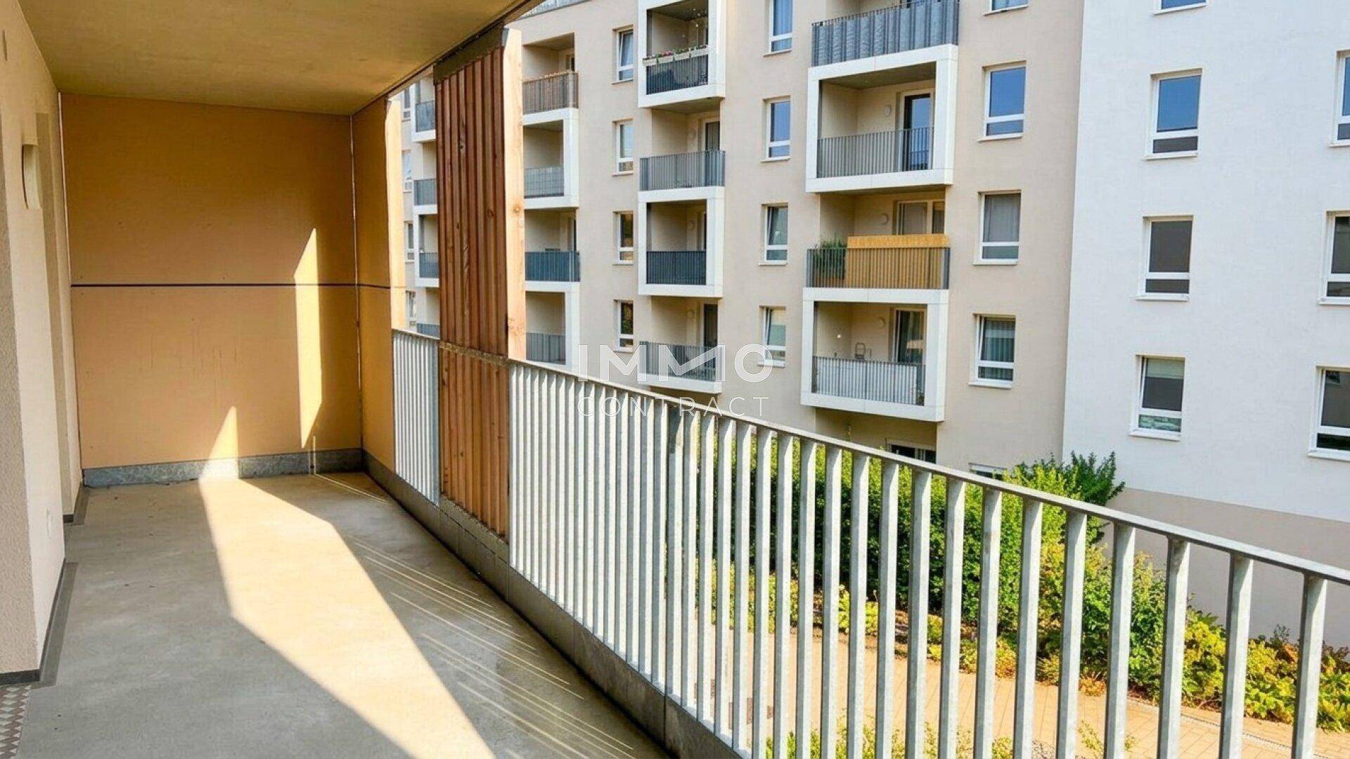 Geräumiger Balkon mit Metallgeländer und Blick auf die umliegenden Gebäude und Grünflächen.