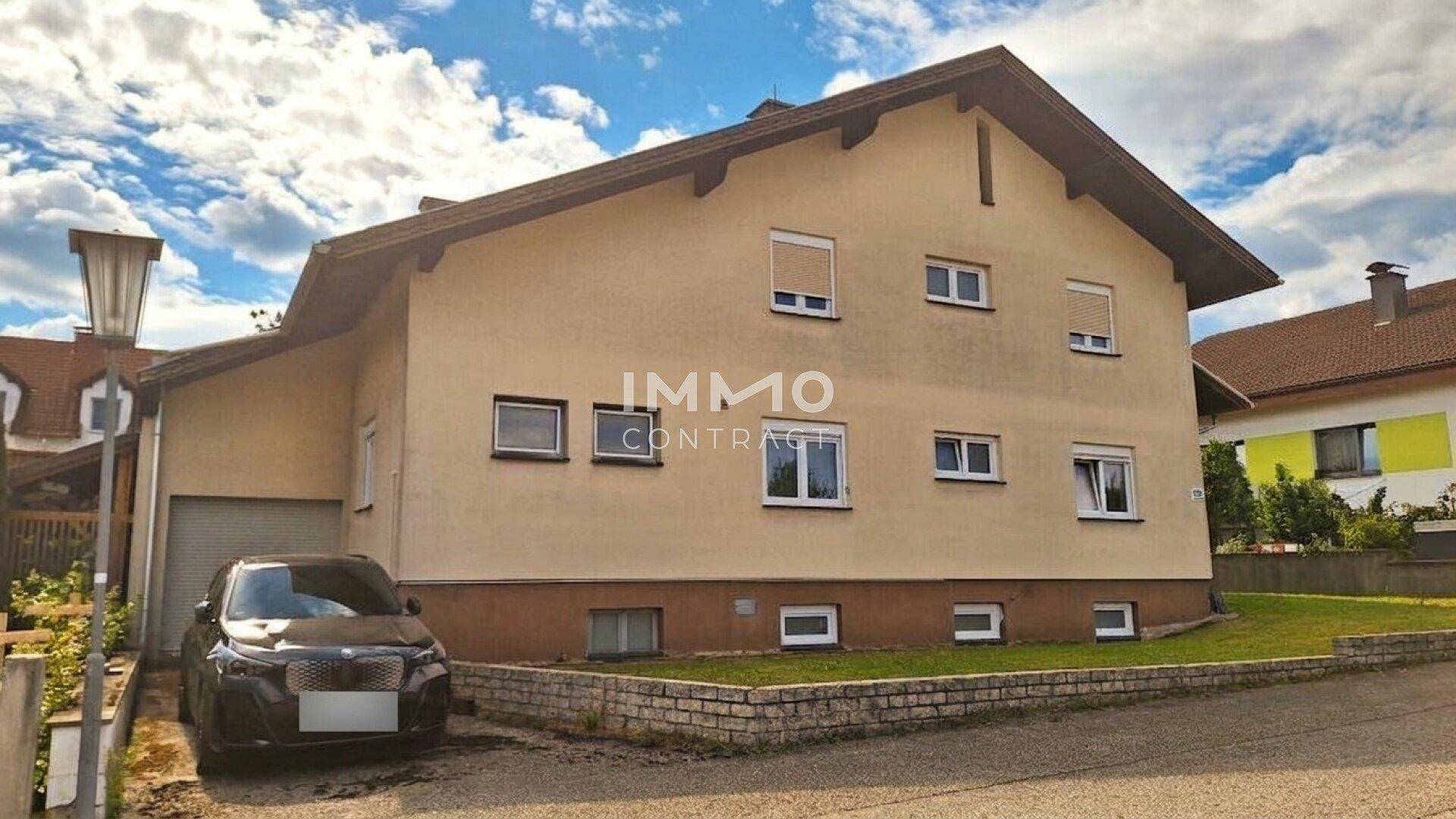Rückansicht des Hauses mit Einfahrt, Garage und Fenstern mit Rollläden.