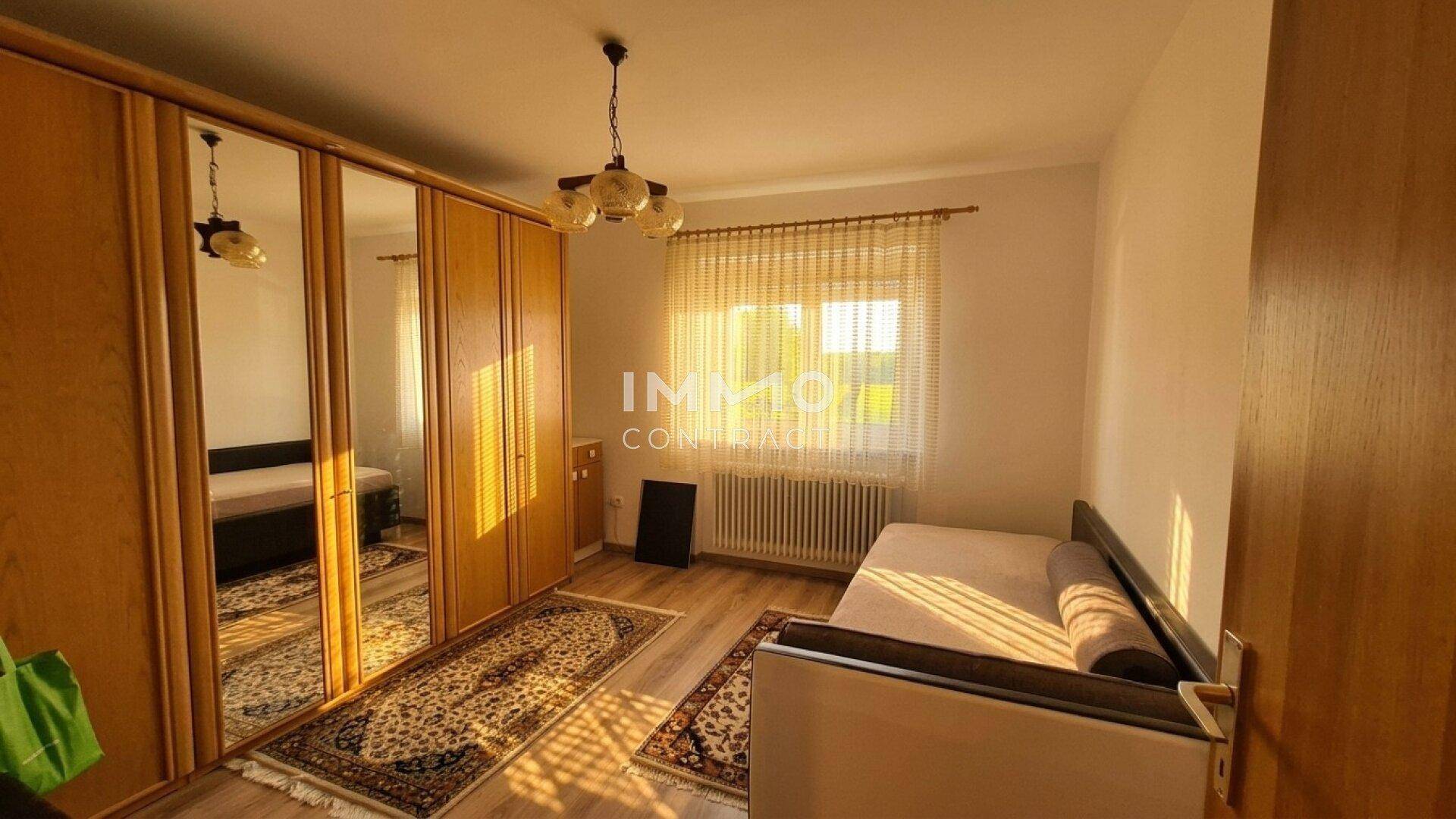 Schlafzimmer mit großem Spiegelschrank, Einzelbett und hellem Laminatboden.