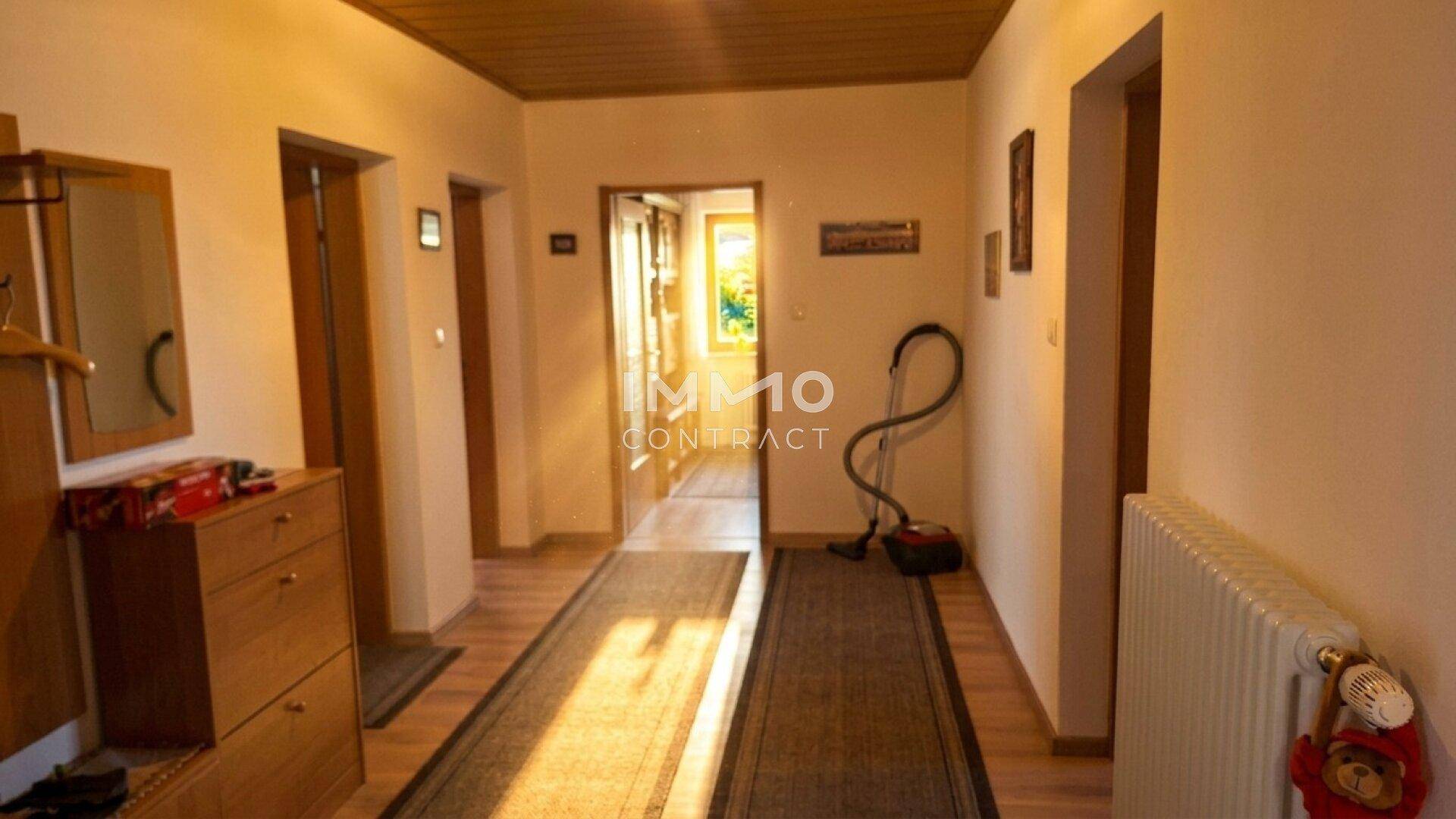 Heller Flur mit Laminatboden, Heizkörper und Zugang zu weiteren Räumen.