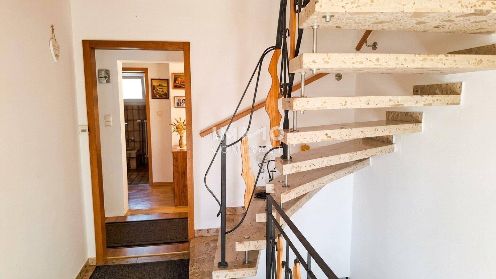 Treppenhaus mit Steinstufen und schmiedeeisernem Geländer, führt in den oberen Bereich.