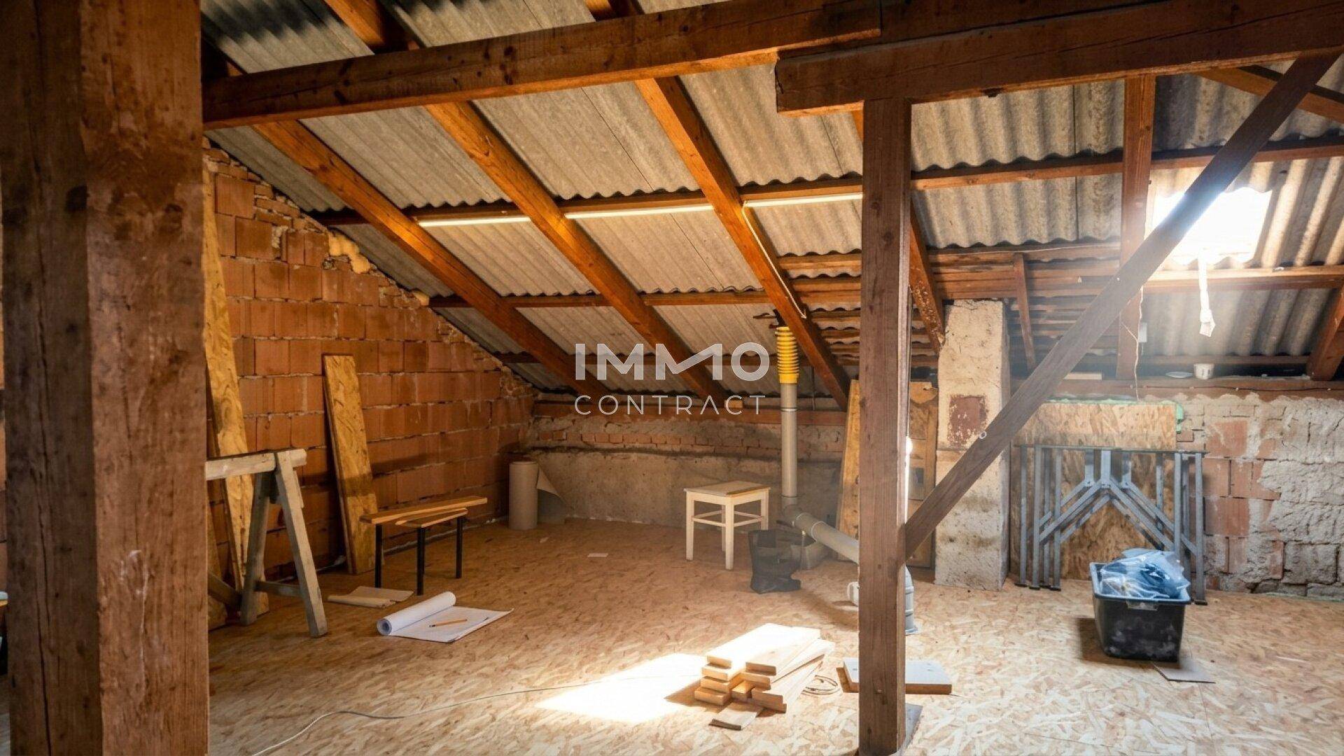 Unausgebauter Dachboden mit sichtbaren Holzbalken und Ziegelwänden, bereit für den Ausbau.