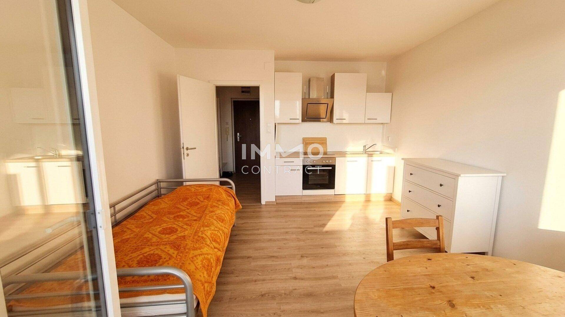 Helles Studio-Apartment mit integrierter Küchenzeile, Bett und Essbereich.