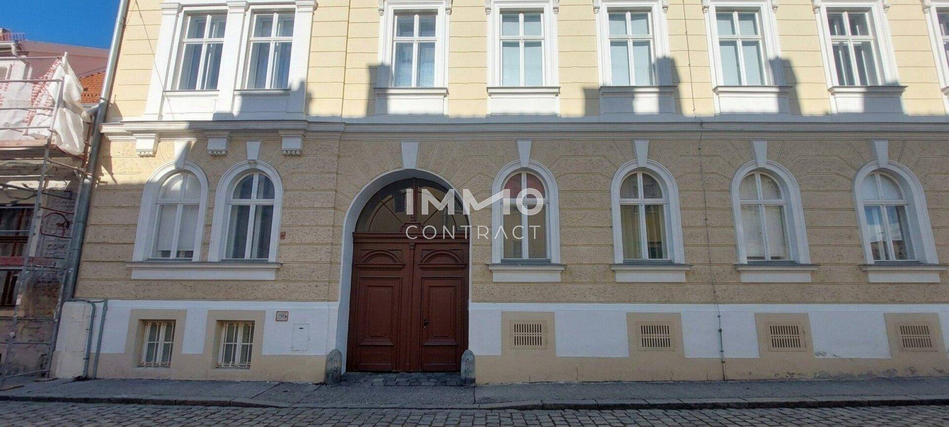 Historische Gebäudefassade mit eleganten Rundbogenfenstern und einer imposanten Holztür.