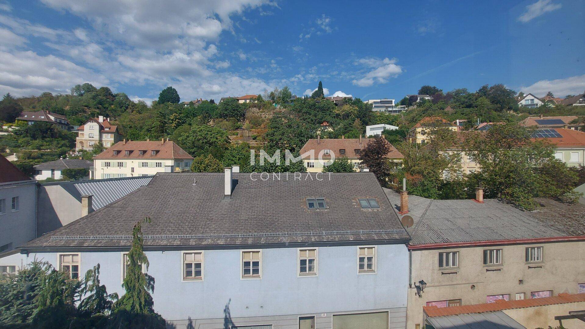 Blick über die Dächer der Nachbarschaft und die bewaldeten Hügel im Hintergrund.