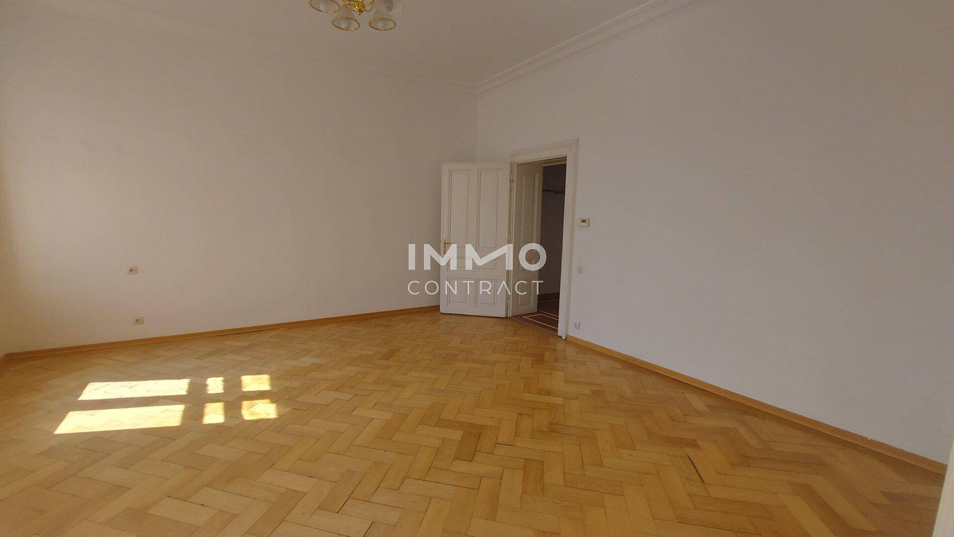 Helles Zimmer mit Fischgrätparkett und weißen Wänden, ideal für Wohn- oder Schlafbereich.