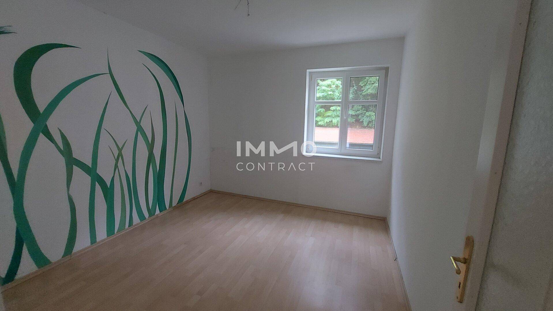 Schlafzimmer mit Holzboden und einer Wanddekoration in Grün, bietet eine ruhige Atmosphäre.