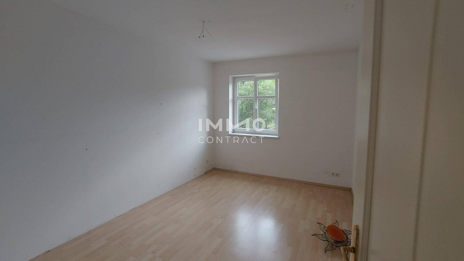 Helles Schlafzimmer mit Holzboden und einem Fenster, das viel Tageslicht spendet.