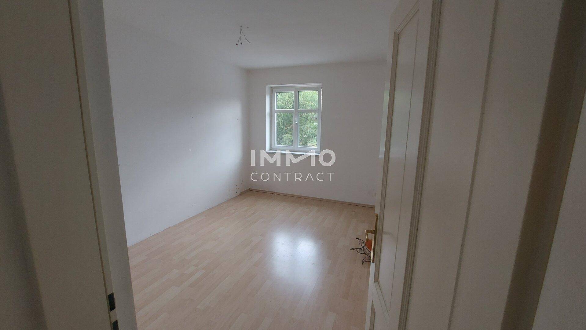 Geräumiges Schlafzimmer mit Holzboden und einem Fenster, das eine angenehme Helligkeit bietet.
