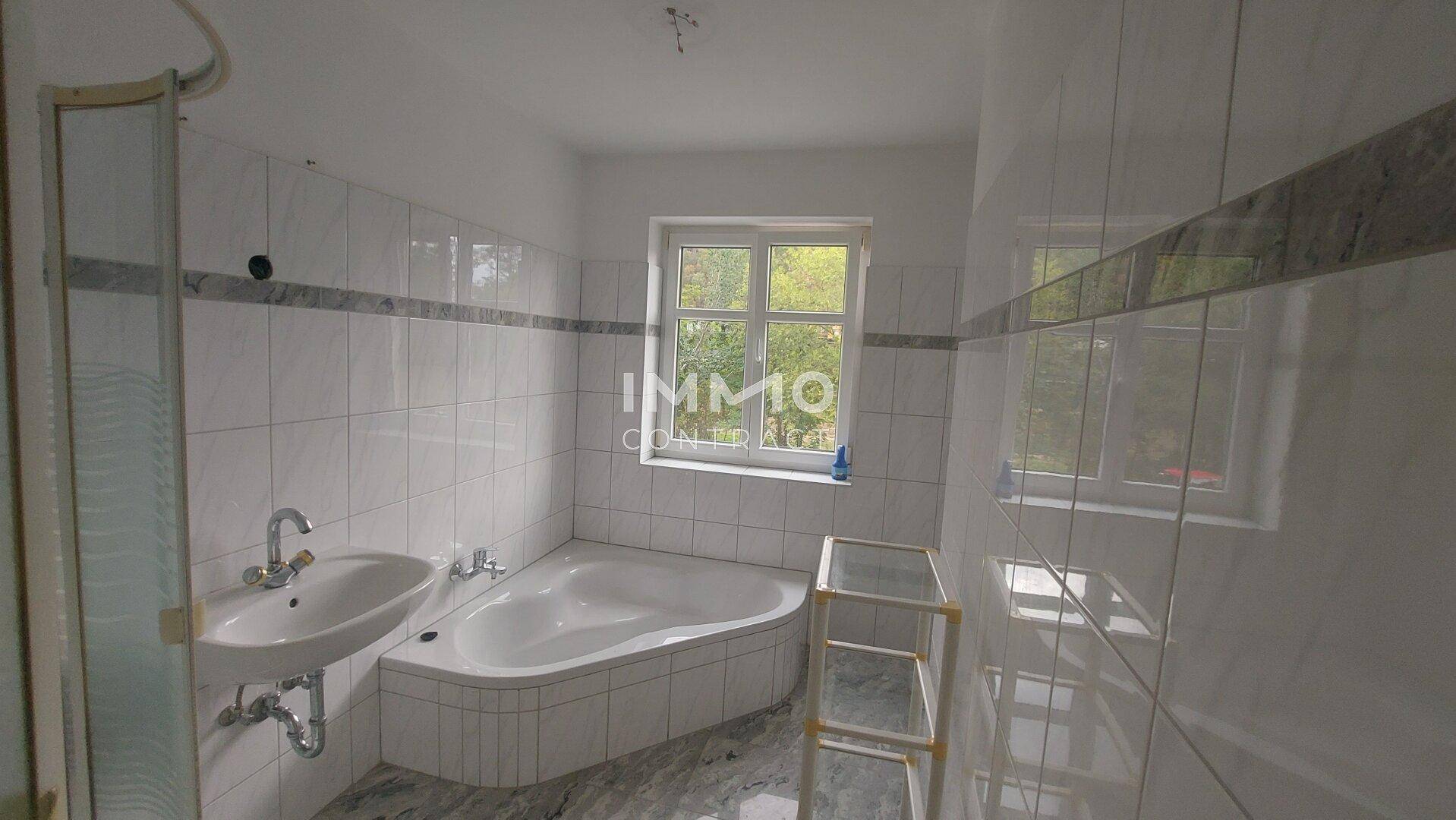 Badezimmer mit Badewanne, Dusche und Fenster, das für natürliche Belüftung sorgt.