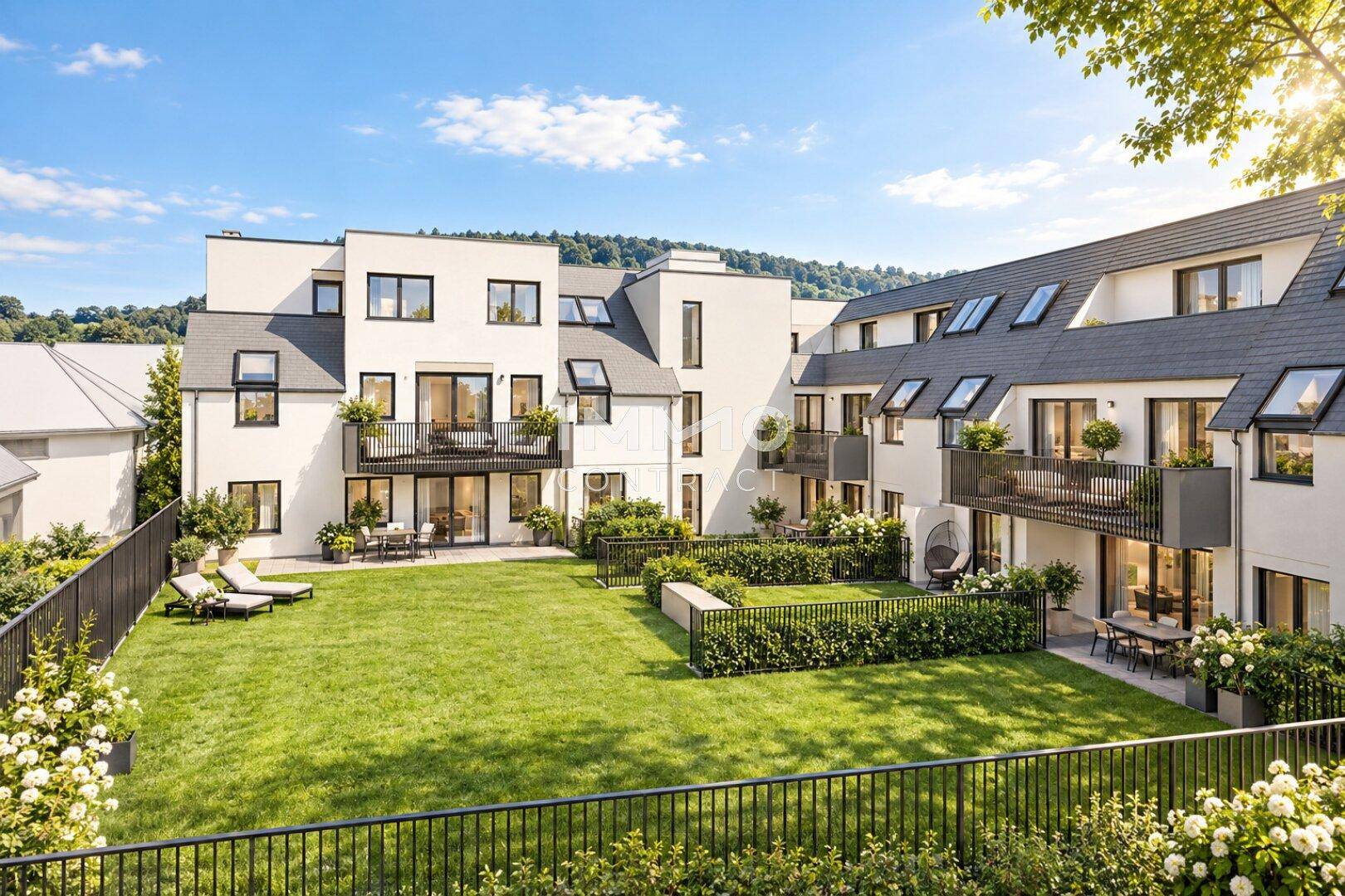 Moderne Wohnanlage mit gepflegtem Gemeinschaftsgarten, Terrassen und Balkonen unter blauem Himmel.