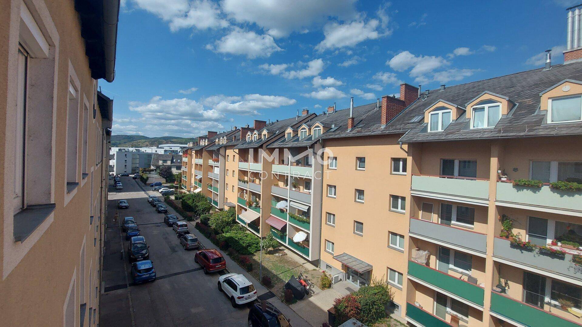 Blick auf eine Wohnstraße mit geparkten Autos und mehrstöckigen Gebäuden.