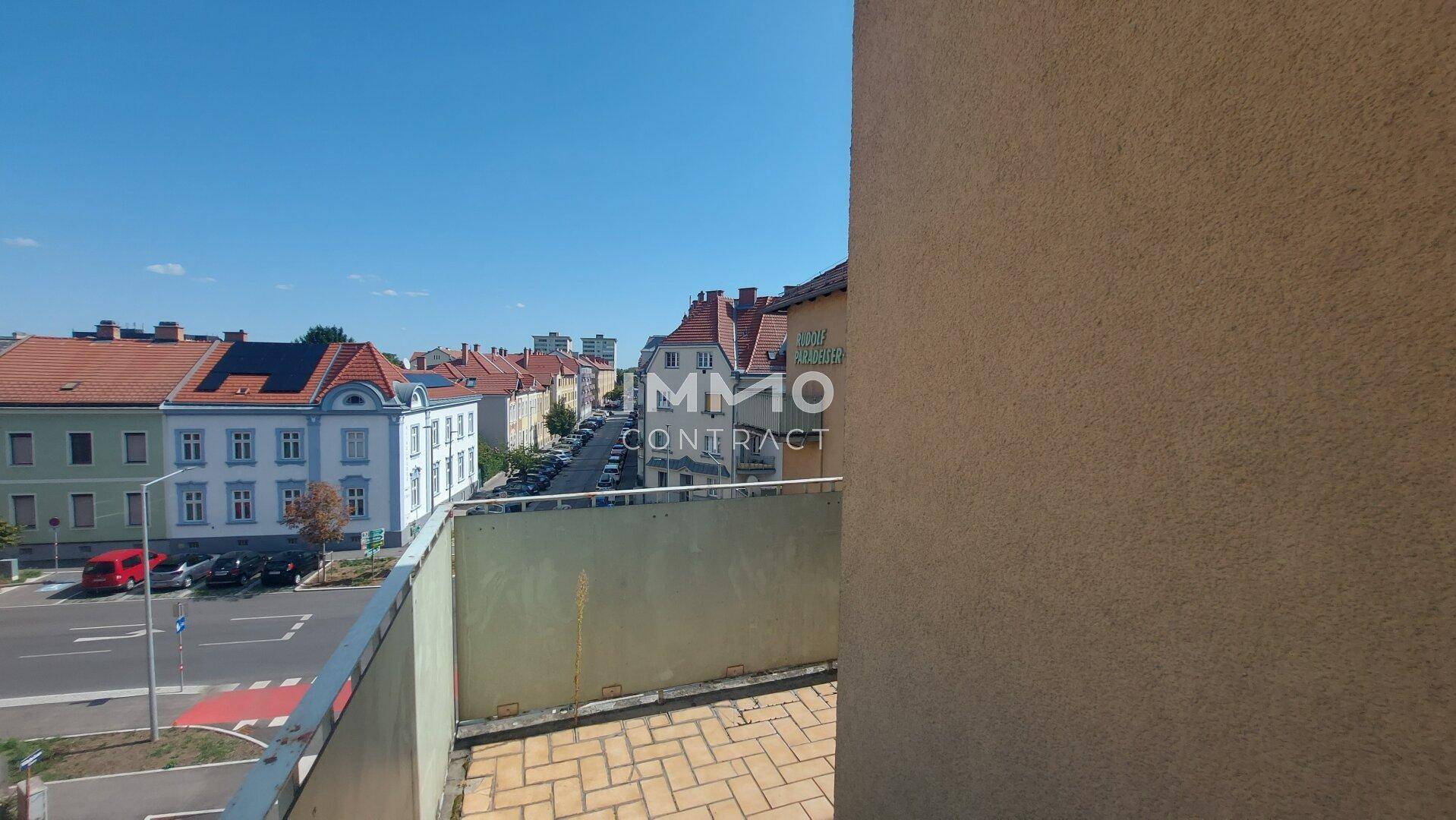 Balkon mit Fliesenboden und weitem Blick über die Stadt und umliegende Straßen.