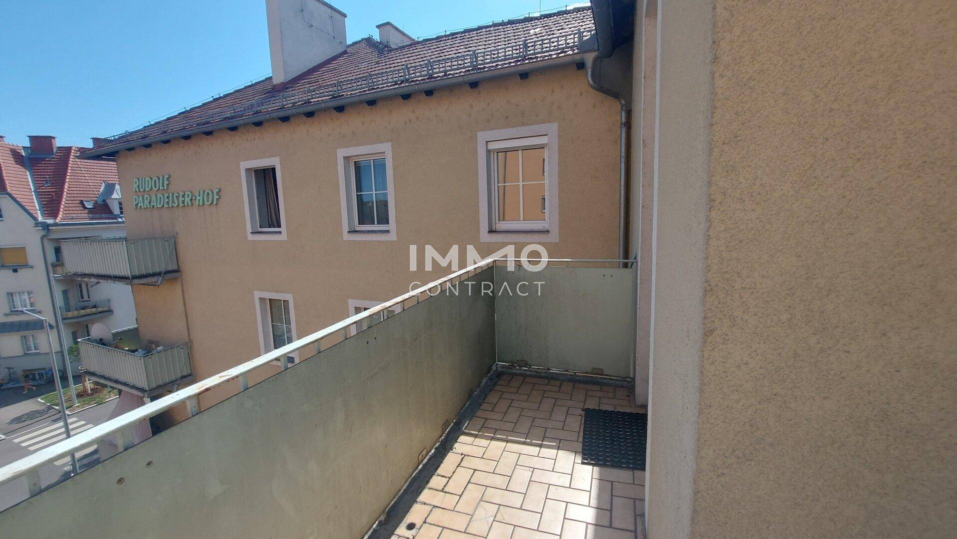 Kleiner Balkon mit Fliesenboden und Blick auf die umliegenden Gebäude.