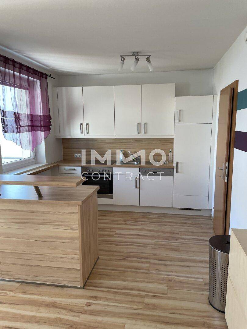 Helle Einbauküche mit weißen Schränken, Arbeitsplatte in Holzoptik und Laminatboden.