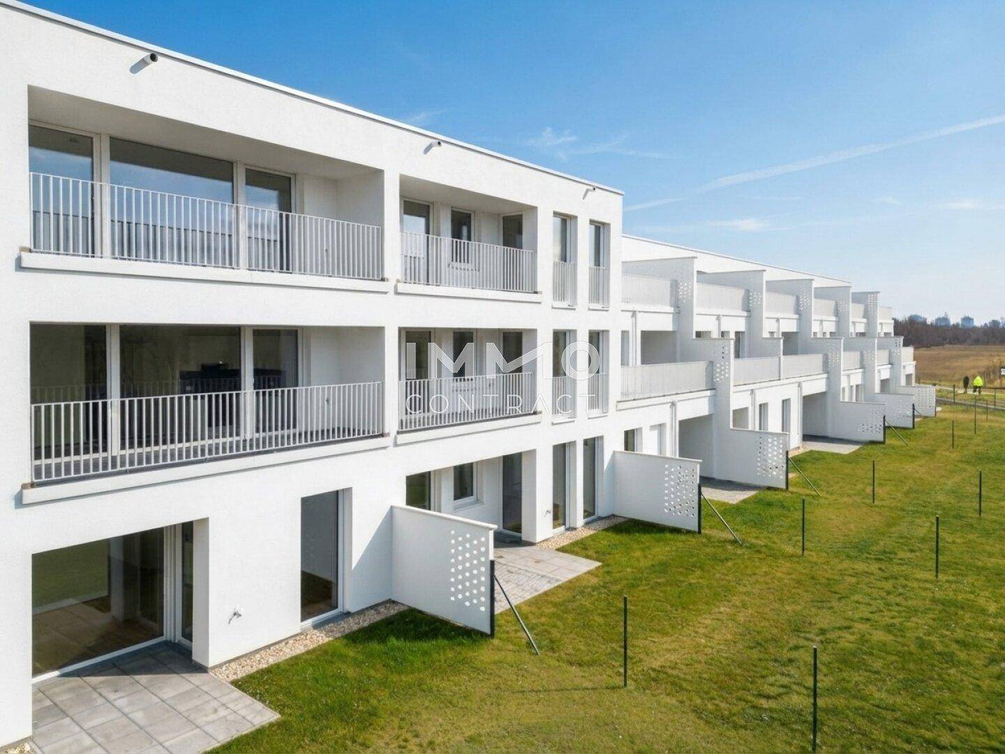 Reihen moderner Wohneinheiten mit privaten Gärten und Balkonen in sonniger Lage.