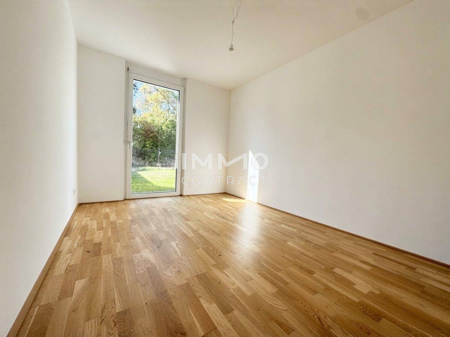 Lichtdurchflutetes Schlafzimmer mit Holzboden und Blick ins Grüne, ideal für Ruhe und Entspannung.
